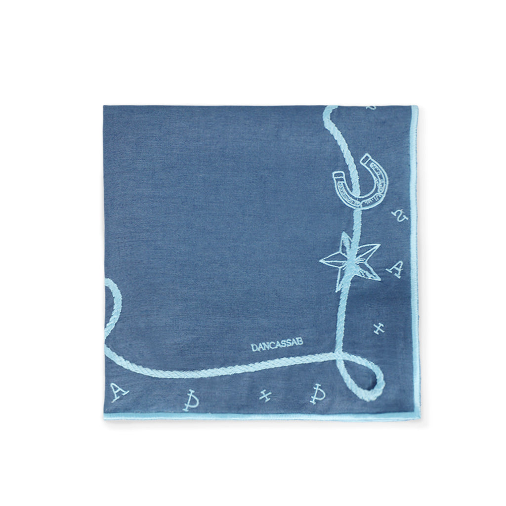 Servilleta Cowgirl en lino azul con motivos vaqueros bordados en azul turquesa, diseñados por Dan Cassab para Zash