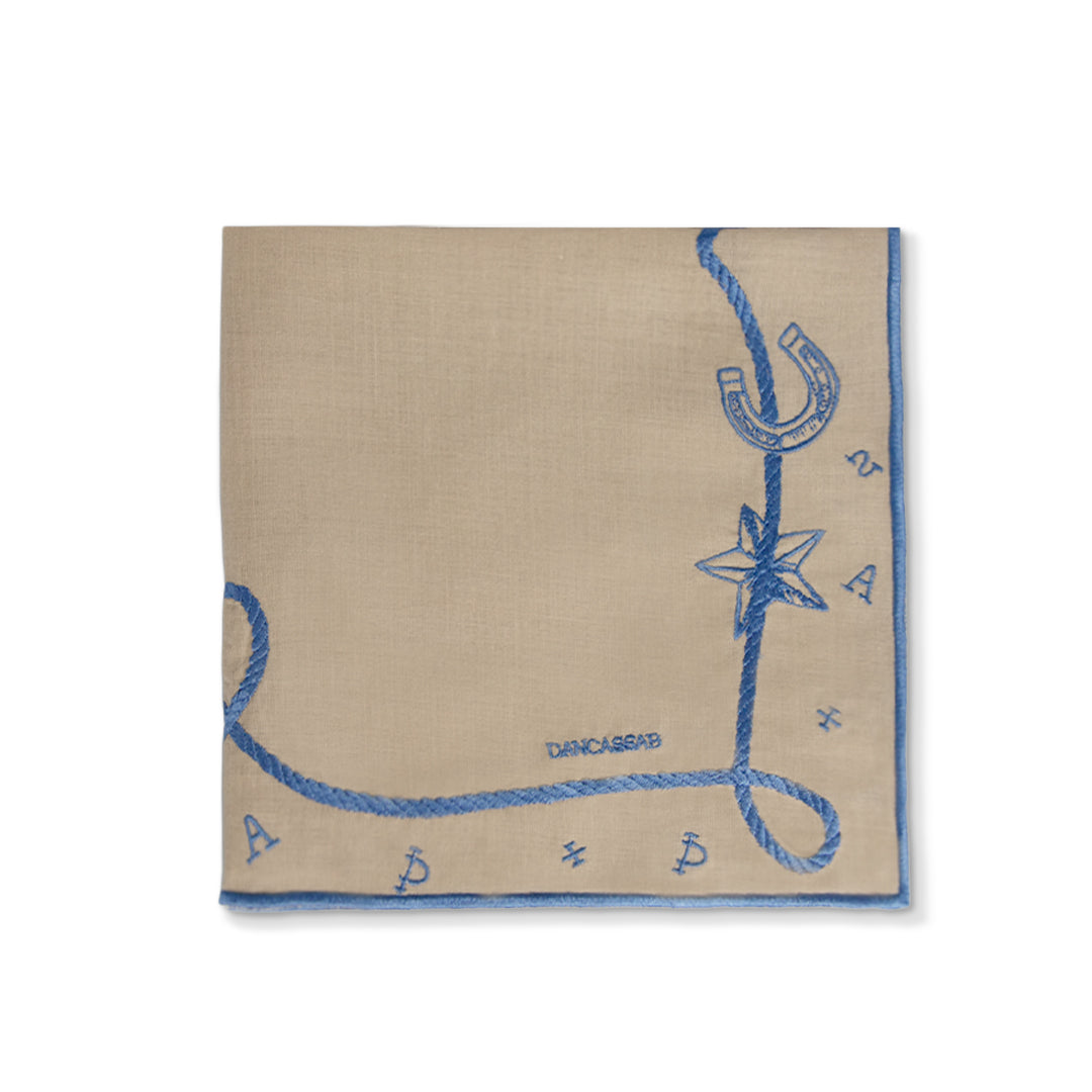 Servilleta Cowgirl en lino caramel con motivos vaqueros bordados en azul, diseñados por Dan Cassab para Zash