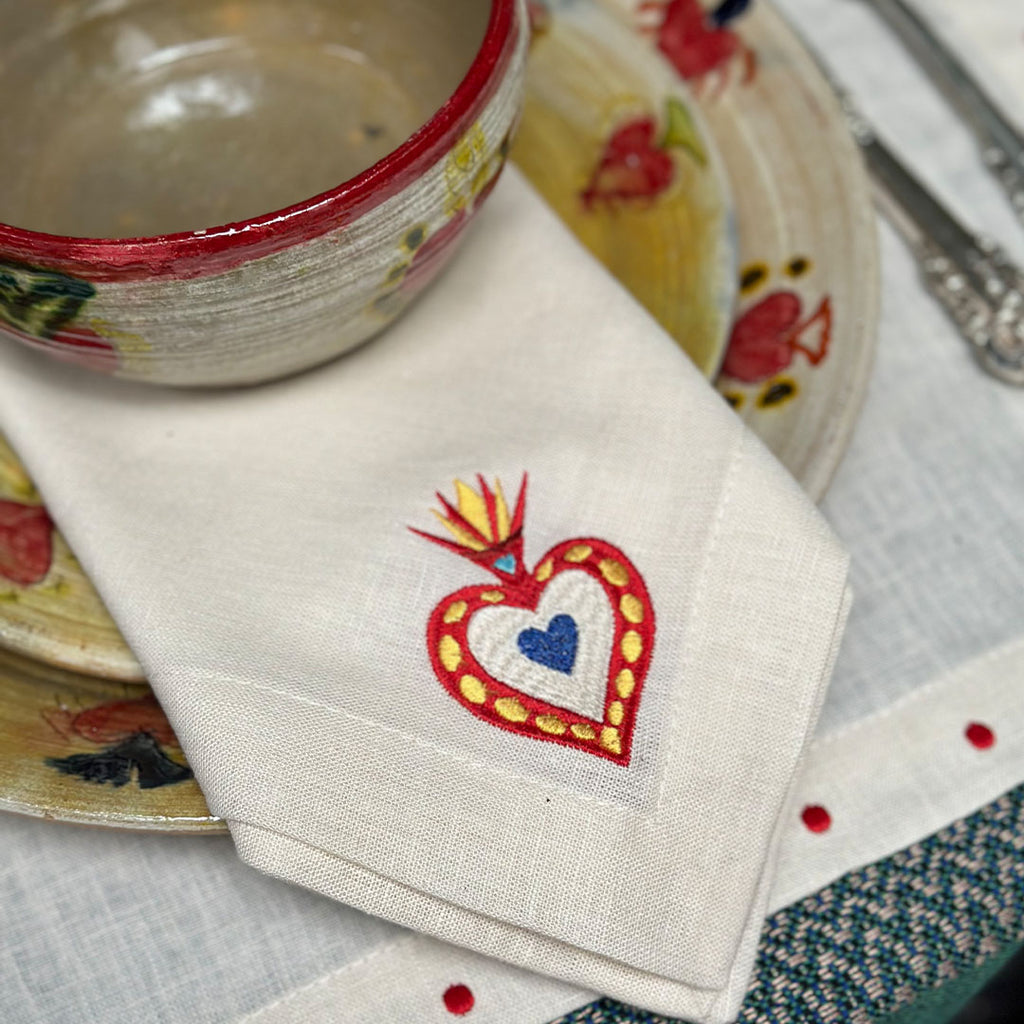 Mantelería Milagritos con Individuales Silvia con Puntitos Rojos y Servilletas Milagritos con Bordado de Corazón en llamas en Lino Arena. Set para 4 personas.