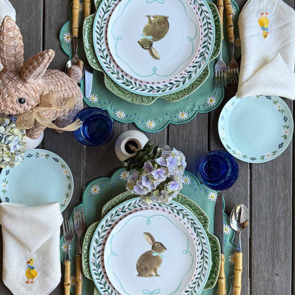 THE DUCKLING ZASHPACK: Set con 4 Servilletas Easter en Lino Ivory con Bordado de Pato, 4 Individuales Pily en Algodón Verde con Bordado de Margaritas y 4 Platos Trinche con Borde de Flores.