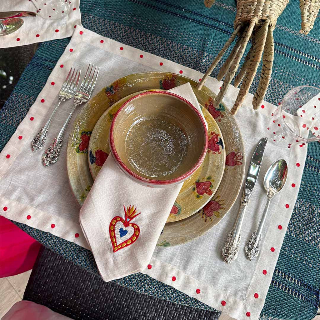 Mantelería Milagritos con Individuales Silvia con Puntitos Rojos y Servilletas Milagritos con Bordado de Corazón en llamas en Lino Arena. Set para 4 personas.