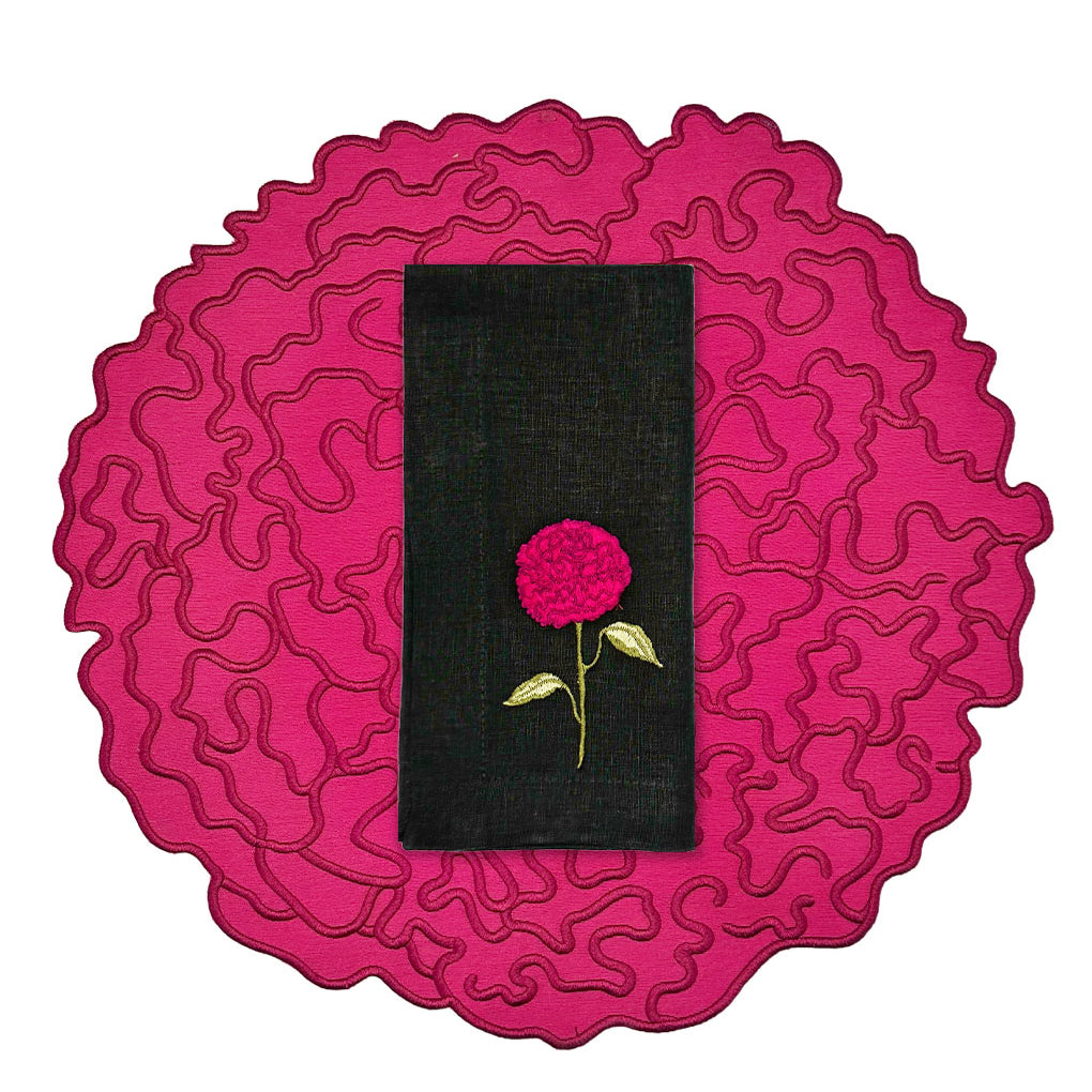 Set de mantelería de Flor de Celosía con individual en forma de flor en fuscia, y servilleta de lino negro con flor bordada, marca Zash