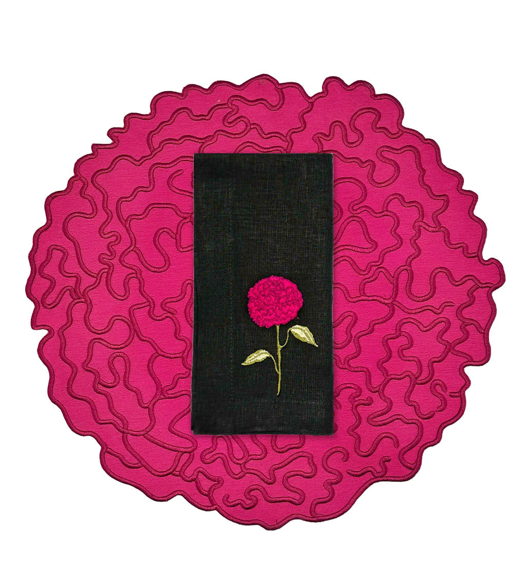 Set de mantelería de Flor de Celosía con individual en forma de flor en fuscia, y servilleta de lino negro con flor bordada, marca Zash