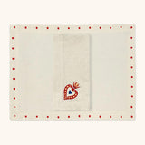Mantelería Milagritos con Individuales Silvia con Puntitos Rojos y Servilletas Milagritos con Bordado de Corazón en llamas en Lino Arena. Set para 4 personas.