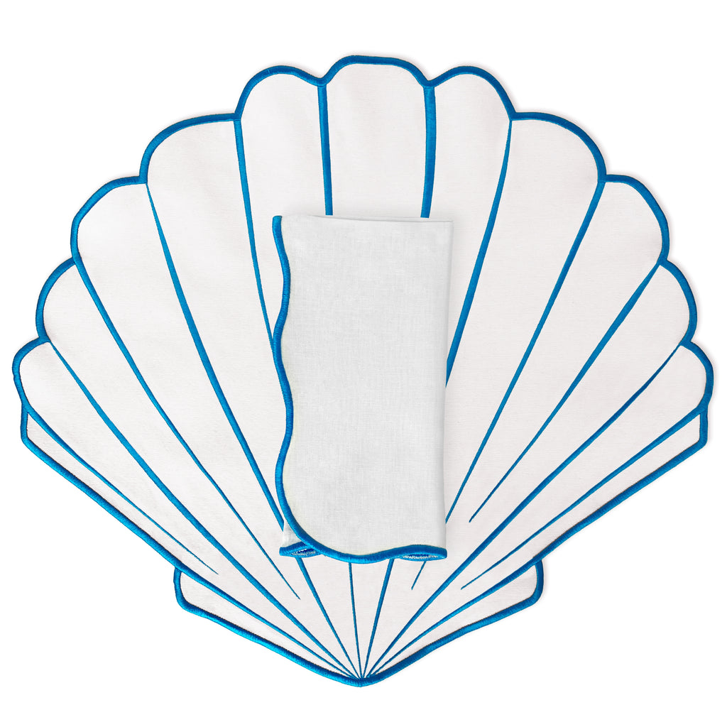 Set de mantelería con mantel individual en forma de concha blanca con bordado azul y servilleta de la marca Zash. Perfecta para mesas de playa o verano