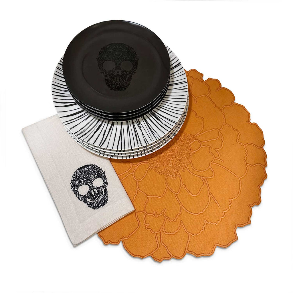 Setting de mesa para celebrar día de Muertos con Individuales en forma de flor cempasúchil, servilleta bordada con calaca, platos trinche y platos de ensalada con calaca, marca Zash