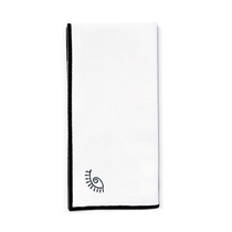 Servilleta de lino blanco con ojo de la suerte y orilla bordada en negro, marca Zash