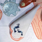 Servilletas Arrecife en Lino Blanco con Bordado de Camarones en tonos de azul y orilla rosa. Set de 4
