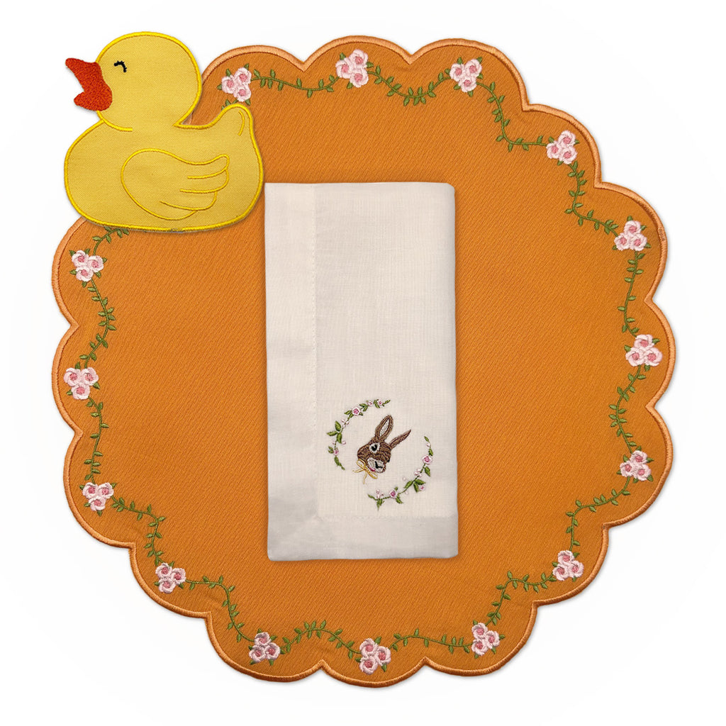 Set de Mantelería Easter con Individuales de algodón naranja con flores bordadas, servilletas de lino Ivory con conejo bordado y cocteleras en forma de patito de hule, marca Zash