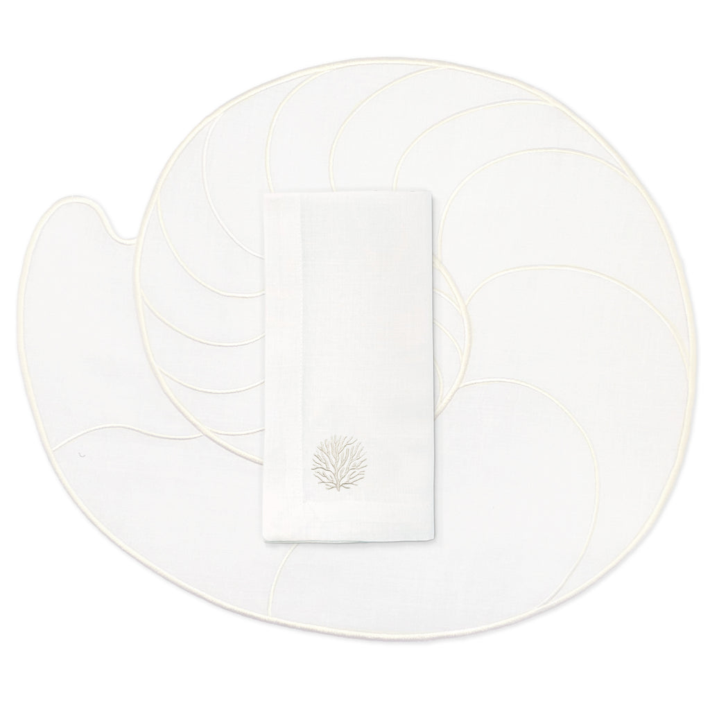 Set de mantelería de mar en lino blanco con individuales en forma de caracol de mar nautilus, y servilletas con bordado de coral en ivory, marca Zash