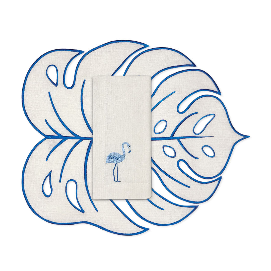 Set de mantelería de lino arena con bordado azul con individuales en forma de hoja monstera y servilleta con flamingo bordado, marca Zash 