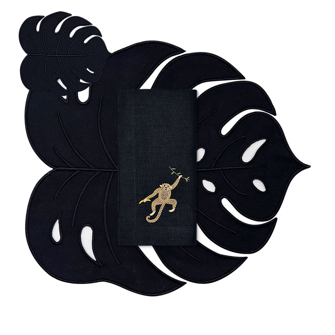 Set de mantelería Tropic en lino negro con individuales y cocteleras en forma de hoja y servilleta con un chango bordado, marca Zash
