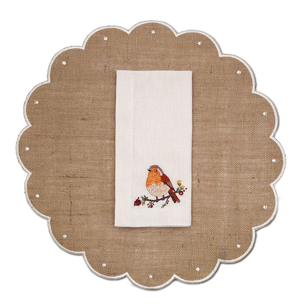 Set de mantelería con individuales de yute natural y orilla bordada en ivory, y servilletas en lino crudo con bordado de pajarito otoñal. Marca Zash