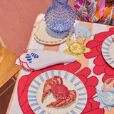 Manteleria Arrecife con Individuales de Anemona Bordado en Algodón Rojo y Servilletas en Lino Blanco con Bordado de Peces Payaso y Orilla Roja. Set para 4 personas