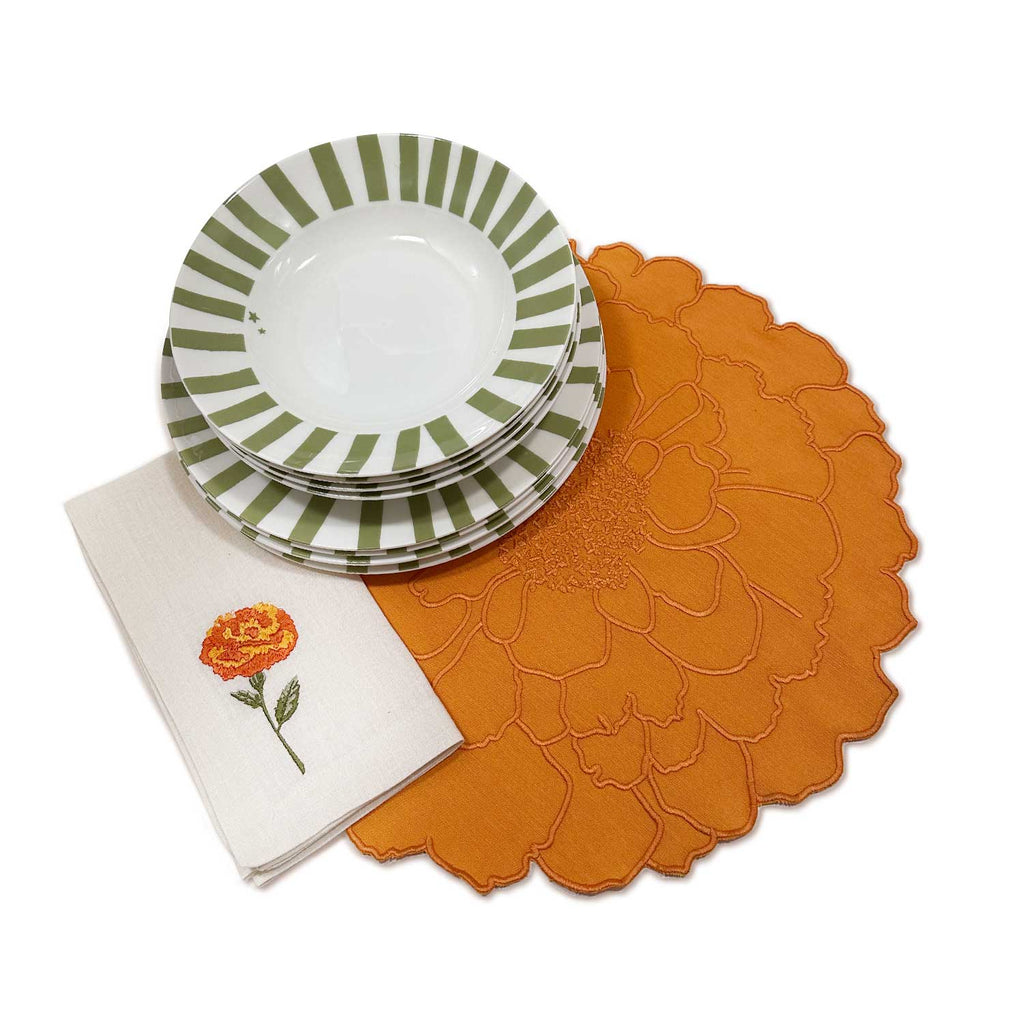 Set de mesa completo con inspiración en la flor Cempasúchil que incluye manteles individuales, servilletas bordadas, platos trinche y platos soperos. Marca Zash