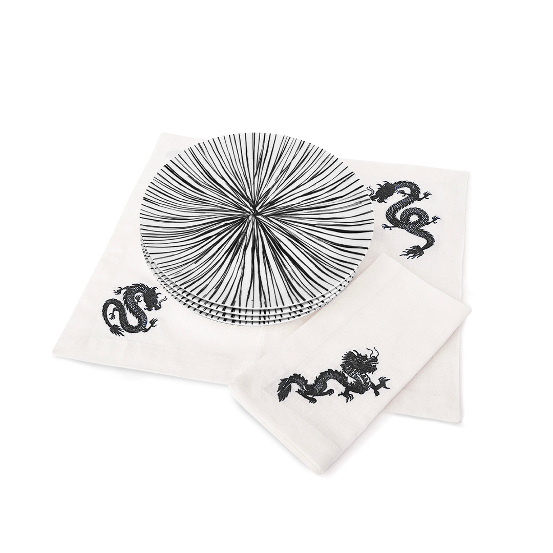 Set de mantelería de lino blanca con dragones negros bordados y platos trinche con rayas negras, marca Zash
