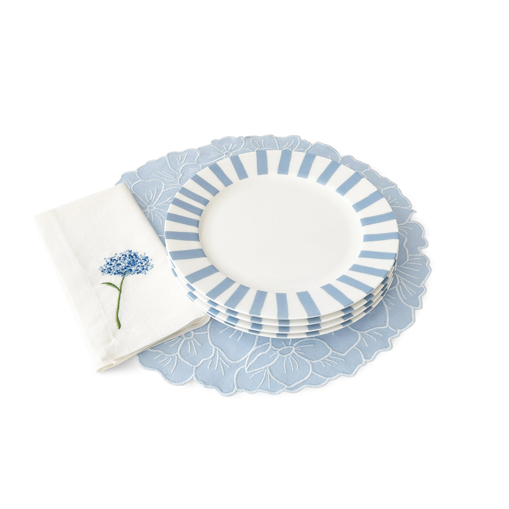 Zashpack blue flower con individuales en forma de flor hortensia en azul, servilletas de lino con flor bordada azul y platos trinche con rayas azules, marca Zash