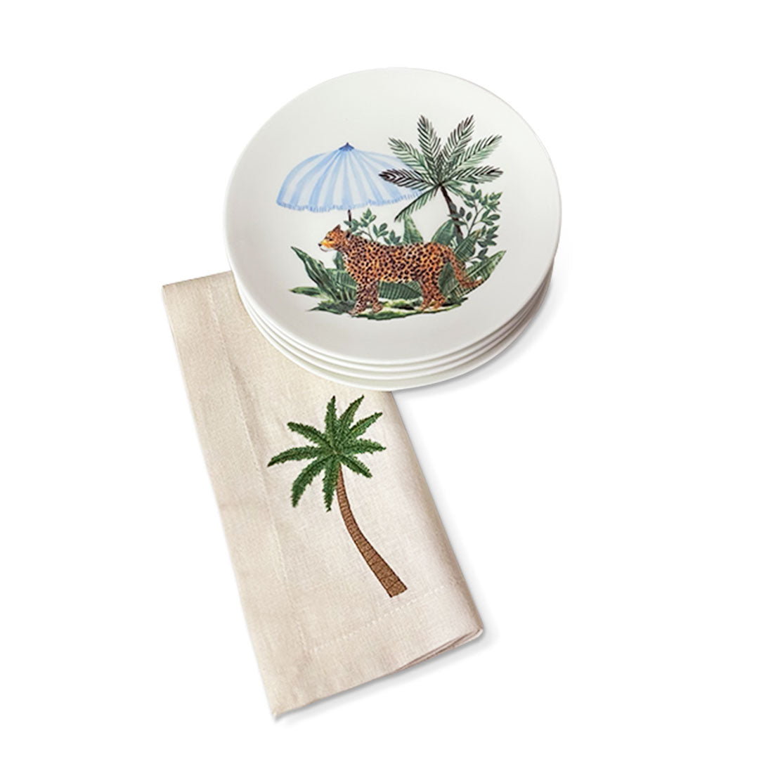 Set de mesa con platos de ensalada de porcelana blanca con leopardo y sombrilla, con servilleta de lino arena con palmera bordada, marca Zash